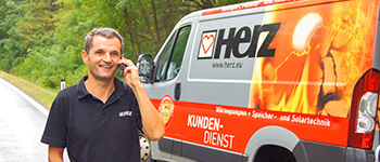 servisný technik stojaci pri aute s označením Herz