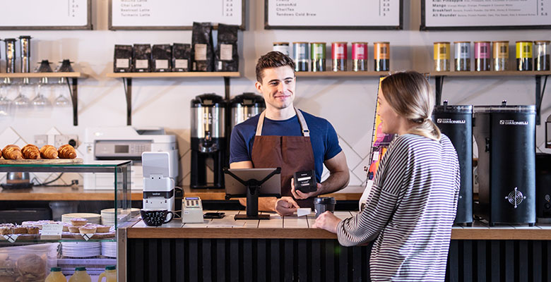Barista v kaviarni obsluhujúci zákazníčku