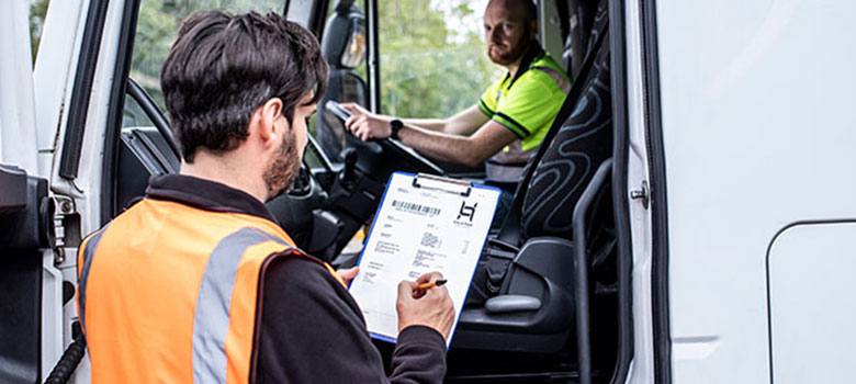 muž v reflexnej veste vypĺňajúci formulár, vodič auta s rukami na volante